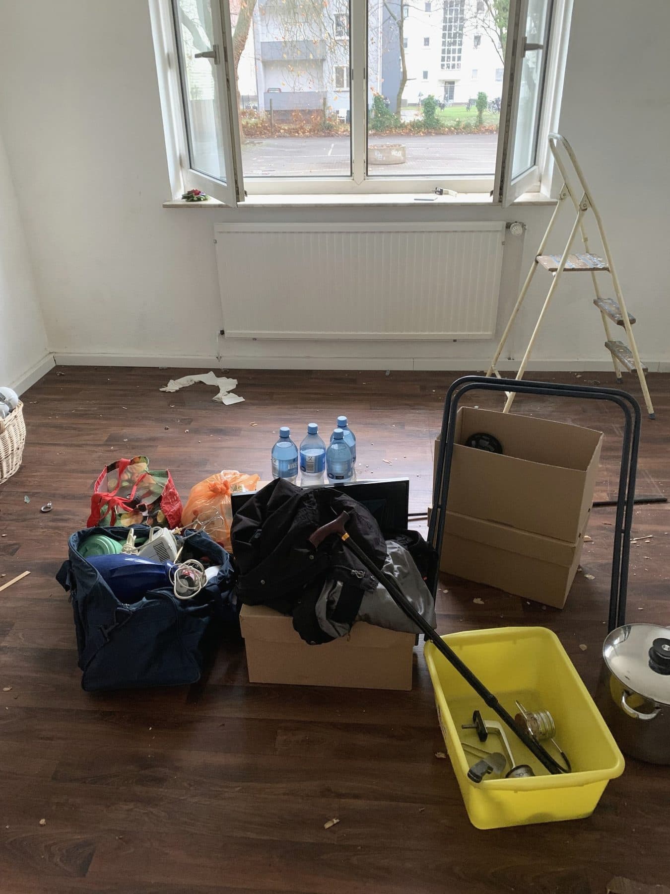 Zusammengetragene Taschen, Kartons und Flaschen in einem leer geräumten Zimmer